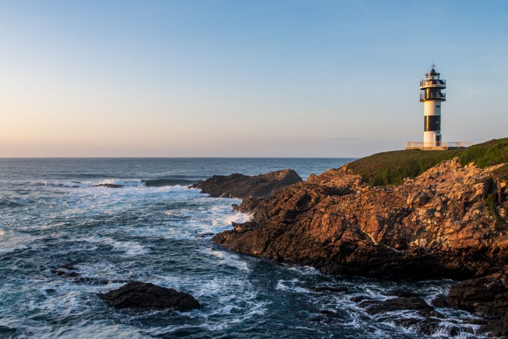 Pancha Lighthouse against a stunning sea at dusk on the rugged coast of Spain.